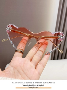 Close-up of frameless gradient pink sunglasses with rhinestone edges and gold metal temples
