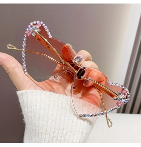 Close-up of heart-shaped rimless sunglasses with gradient lenses and rhinestone butterfly detail