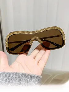 Gros plan sur des lunettes de soleil sans monture avec strass dorés et verres teintés marron