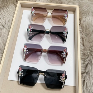 Frameless rhinestone sunglasses with gradient lenses in various colors on a luxury display