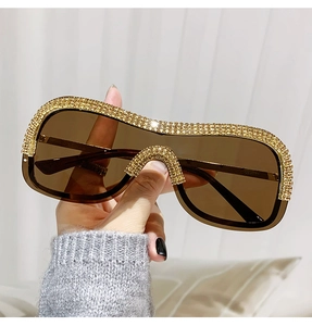 Détail de lunettes de soleil punk sans monture avec verres marrons et strass dorés