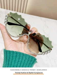 Détail de lunettes de soleil sans monture vert clair avec bords ondulés et strass