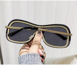 Détail de lunettes punk sans monture avec cadre en métal doré et bord à texture d'engrenage
