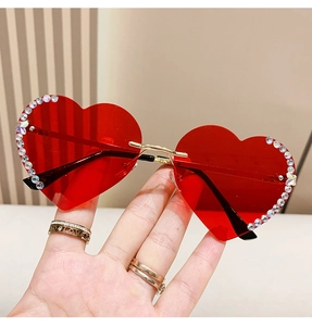 Detailansicht der roten randlosen Herz-Sonnenbrille mit Strasskanten in der Hand