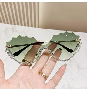 Détail de lunettes de soleil sans monture vert clair avec strass et branches dorées