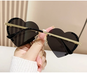 Nahaufnahme der herzförmigen Sonnenbrille mit schwarzen Gläsern und Goldbügeln