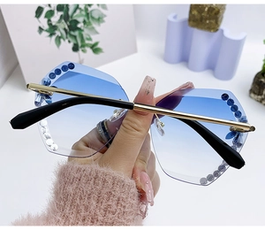 Détail de lunettes de soleil sans monture à verres dégradés bleus et cristaux décoratifs