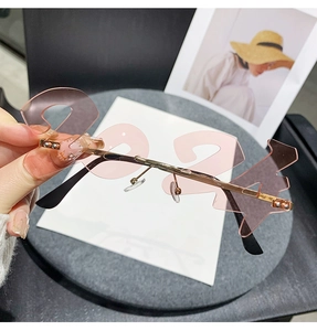 Close-up of pink rimless sunglasses in 2024 number shape with gold metal temples