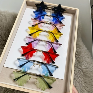 Star shaped rimless sunglasses in eight vibrant colors on a wooden tray with fur background