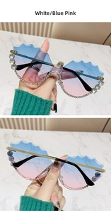 Détail des lunettes de soleil ondulées avec dégradé bleu-rose et cristaux brillants