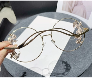 Close-up of gold rimless sunglasses featuring an intricate dragon metal side decoration