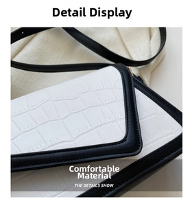Detail of white crocodile embossed leather bag with black contrast trim and sleek finish