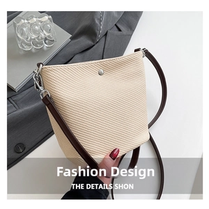 Détail du sac seau en paille tressée avec bandoulière en cuir marron et boucle métal