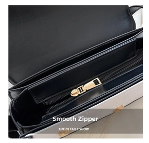Detail of smooth gold zipper and dual-compartment interior of black and white handbag