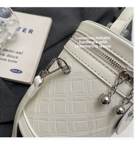 Detail der weißen Eimer-Tasche aus geprägtem Leder mit glänzenden silbernen Beschlägen