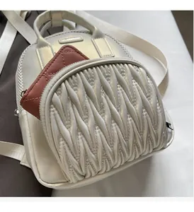Detail view of white ruched backpack showing front zip pocket with brown coin purse inside