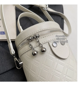 Detailansicht der cremefarbenen Stepptasche mit Doppelreißverschluss und Silberkugeln