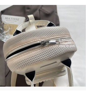 Detail of smooth silver metal zipper and breathable white mesh texture on the backpack