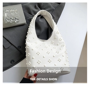 Detail of white hobo bag with 3D floral rivets on lychee texture leather surface