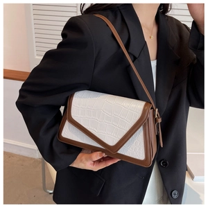 Close-up of white crocodile pattern texture with brown leather trim on the shoulder bag