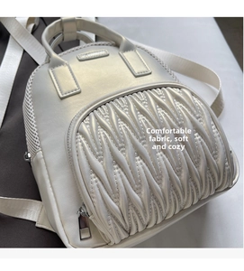 Macro detail of quilted front pocket and silver zipper on white faux leather mini backpack