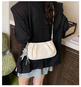 Detail of off-white pleated cloud bag with silver star pendant on a black blazer