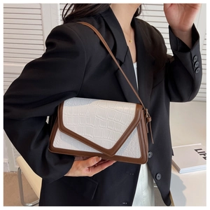 Close-up of crocodile textured white leather shoulder bag with dark brown trim detail