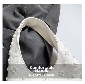 Close-up of white lychee pattern leather handbag with decorative spherical studs