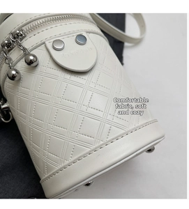 Detail der weißen gesteppten Eimer-Tasche mit silbernem Reißverschluss und Kugelanhänger