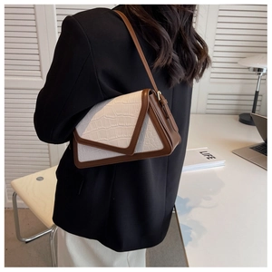 Detail of a minimalist shoulder bag with brown crocodile pattern and white contrast