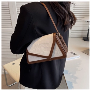 Detailed view of crocodile pattern leather shoulder bag with geometric flap and brown trim