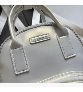 Detail of pearl white bag with Nomonora metal logo and durable zip-top closure