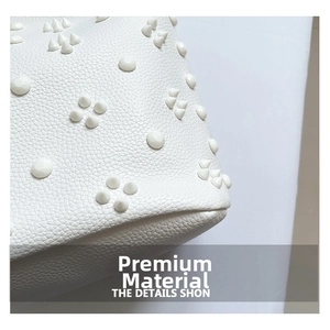 Detail of white lychee grain leather tote bag featuring stylish conical rivet decorations
