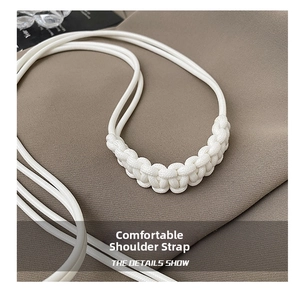 Detailed view of a white woven shoulder strap featuring intricate braided nodes and texture