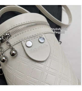 Detailansicht der weißen gesteppten Zylindertasche mit silbernen Nieten und Reißverschluss