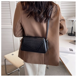 Chic black crocodile embossed crossbody bag styled with a brown blazer and white trousers