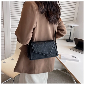 Detail of black crocodile texture shoulder bag on model with minimalist office background