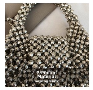 Detailed close-up of woven silver faceted beads with a metallic finish on a handbag