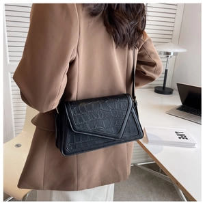 Detail of black crocodile texture shoulder bag with V-shaped asymmetrical flap design
