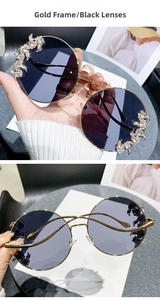 Close-up of gold metal frameless sunglasses with rhinestone dragon detail and black lenses