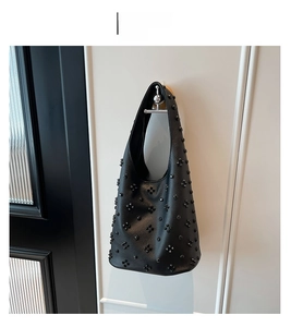 Detail of black hobo bag with retro rivet floral pattern and lychee texture