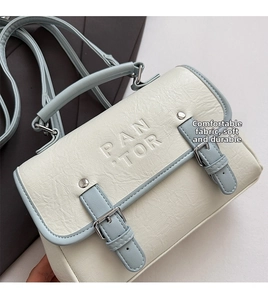 Close-up of a cream and blue leather handbag with silver buckles and PAN TOR engraving