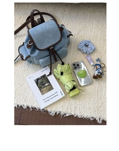Detail of vintage denim backpack with brown leather trim and metal buckles on plush carpet