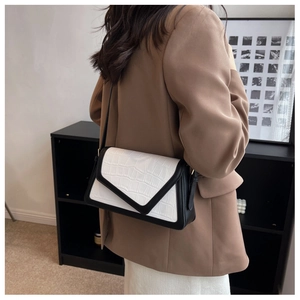 Side view of contrast shoulder bag with white croc-pattern flap and black leather body
