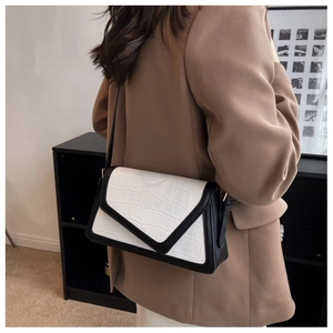 Model wearing a chic black and white contrast crossbody bag with crocodile texture detail