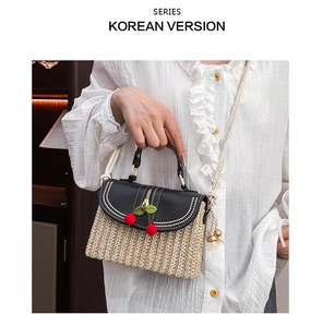 Detailed view of straw weave texture and black leather flap with cherry charm