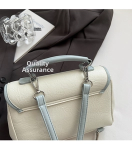 Close-up of elegant cream leather handbag with blue trim and silver hardware details