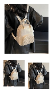 Close-up of cream mini backpack featuring pleated front pocket and dual zipper detail