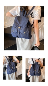 Detail of dark blue denim backpack featuring metal buckles and vintage rivet pockets