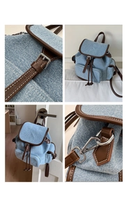 Detail view of denim backpack showing silver buckles, brown leather trim, and white stitching